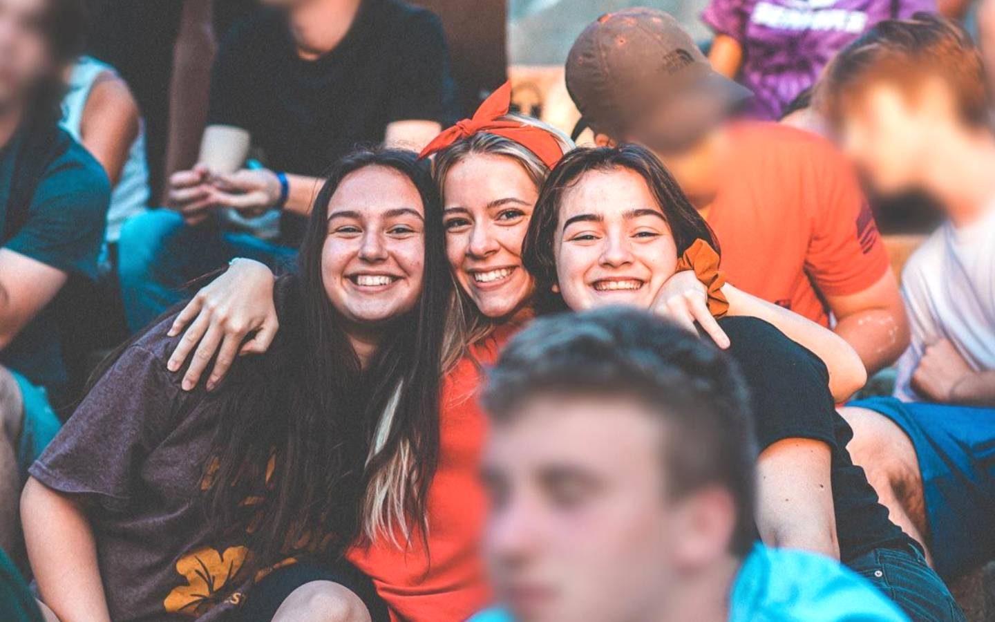 three smiling girls and passersby with face blurring effect